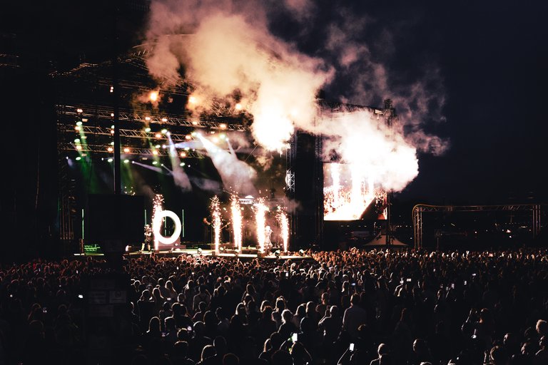 The crowd in front of the main stage at the Stockholm Culture Festival. Night. A pyrotechnic display lights up the stage.