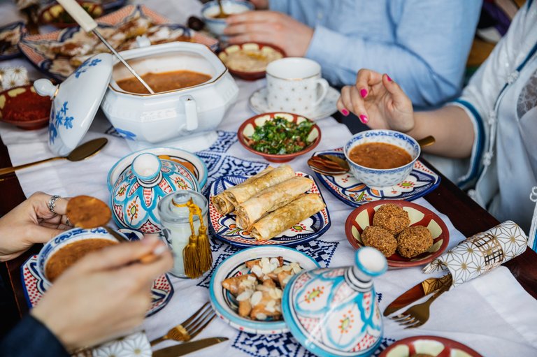 People gathered around a table with traditional dishes and soup during an iftar meal in Ramadan.