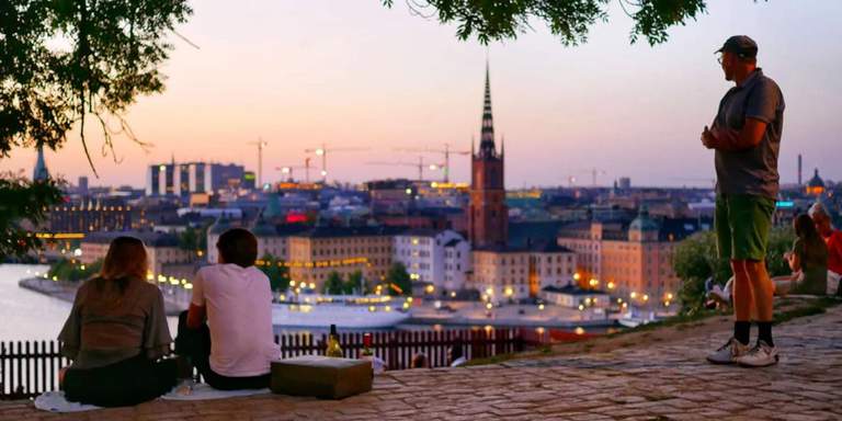 Sommar i Stockholm. Utsikt över Riddarfjärden från Monteliusvägen. Tre människor som njuter av utsikten en mild sommarkväll.