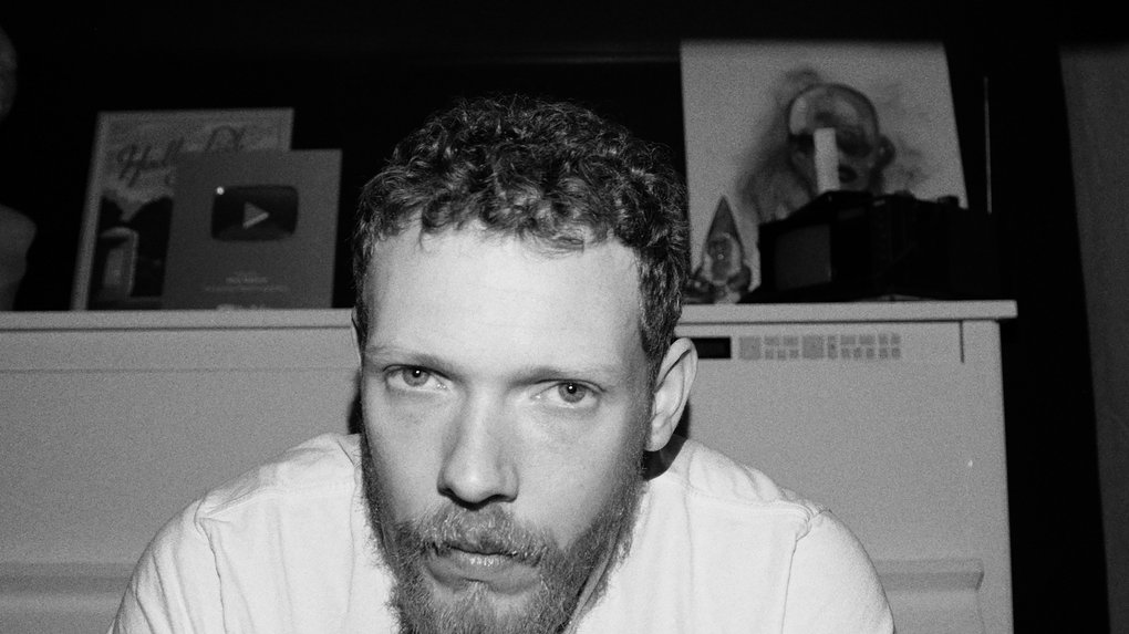 A blond man in front of a white piano.