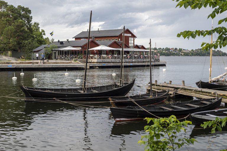 Wooden boats and a red wooden house with a terrace by the quay.