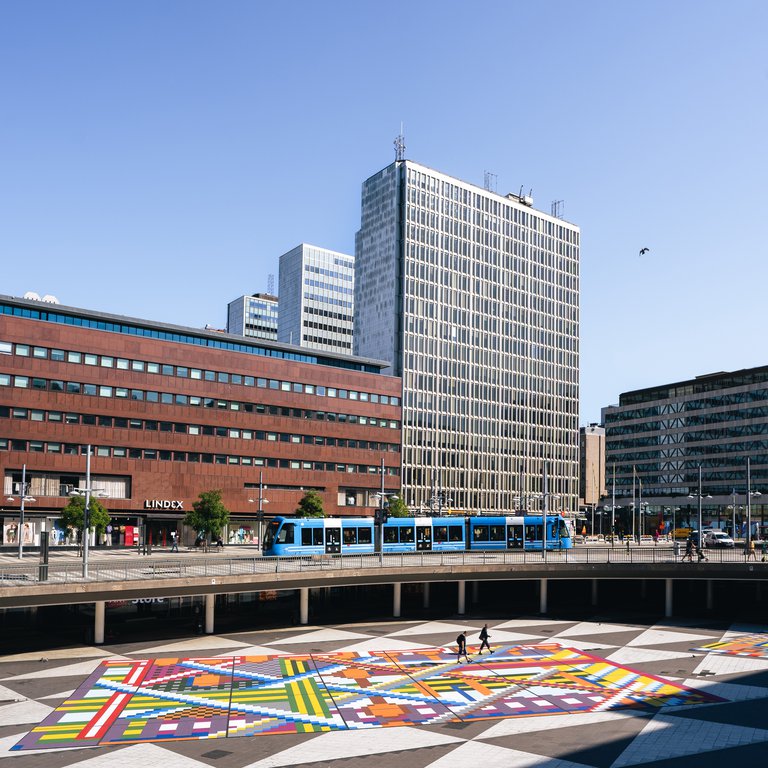 Architecture in Stockholm. Sergels Torg square in central Stockholm. Sunny summer's day. Skyscrapers and tramcars are visible. The tiles covering the square have been covered by a colorful tile mat.