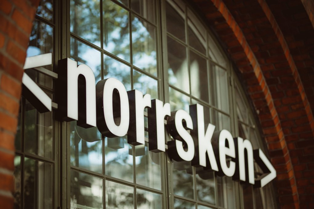 Close-up of the “<norrsken>” sign on a building with glass windows and brick arches.