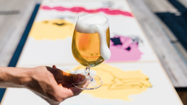 A hand holding a glass of beer.