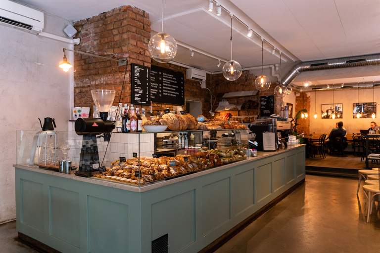 Cafées in Stockholm, Café Pascal in Vasastan. People are sitting in the popular Café on Odeplan. The interior design is light and rustic, and the counter is overflowing with cinnamon buns, croisants and other pasteries.