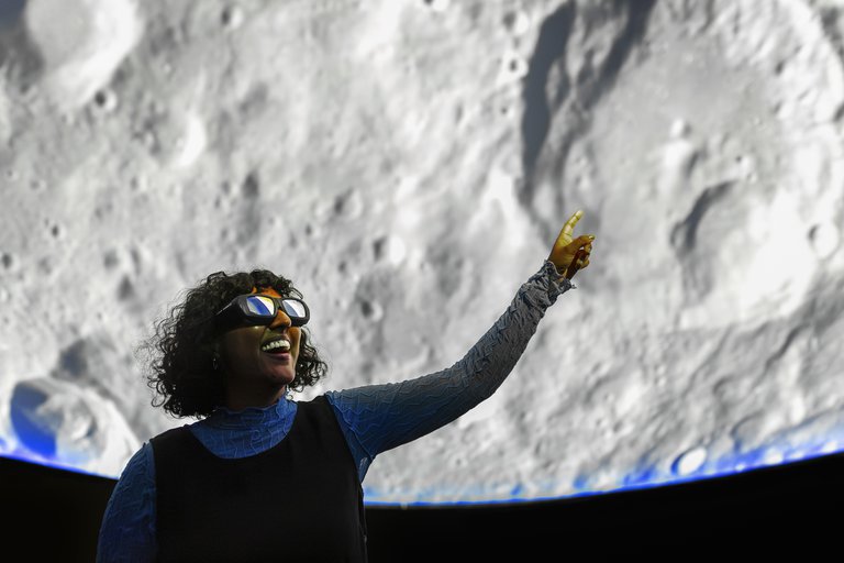 A person in VR glasses smiling and pointing at the Earth surface