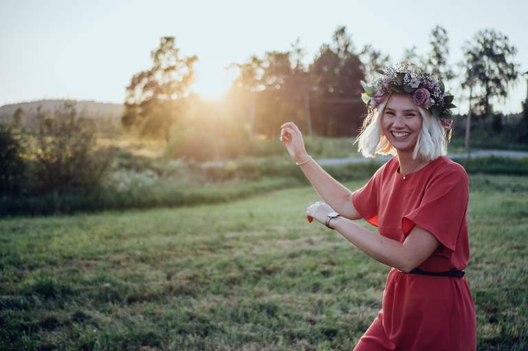 Midsommar i Stockholm. A woman is dancing on a meadow. Sunset.