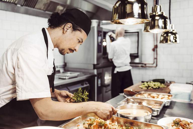 A chef sprinkles herbs into a pan in a Stockholm restaurant.