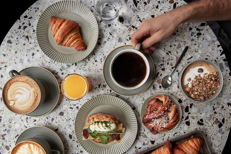 Cafées in Stockholm. A table set for fika at Komet in Stockholm. Coffee, sandwich, cinnamon bun and more.