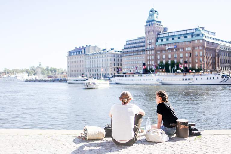 Summer in Stockholm. Two young people chill-out by Nybrokajen in central Stockholm on a warm summer day. Across the water you can see Radisson Hotell.
