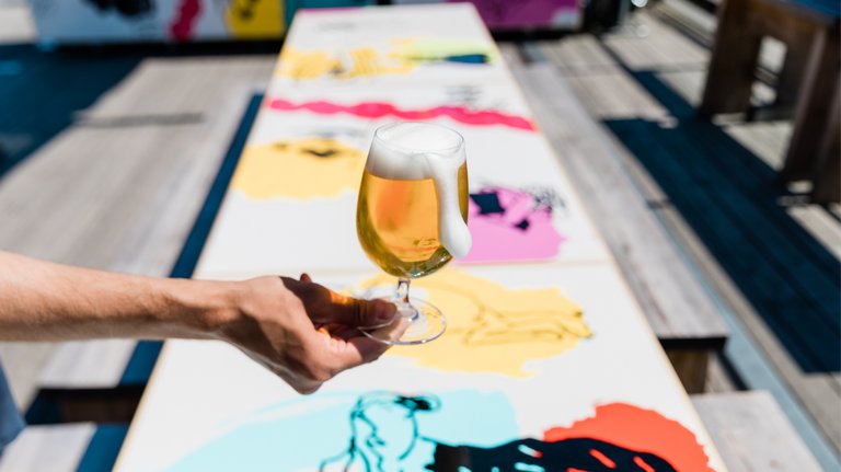 A hand holding a glass of beer.