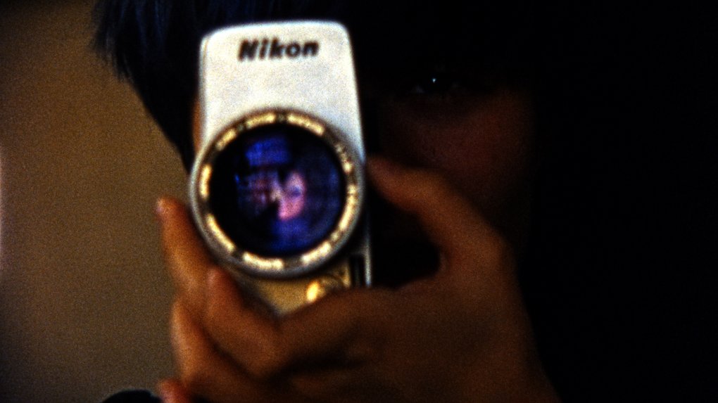A hand holding a Nikon camera.