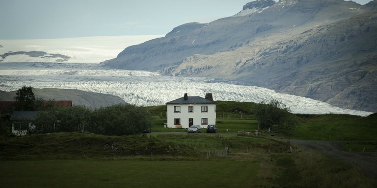 A house on a sea coast with a mountain in the background.
