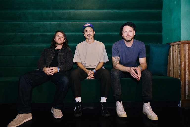 Three men sitting on a sofa.