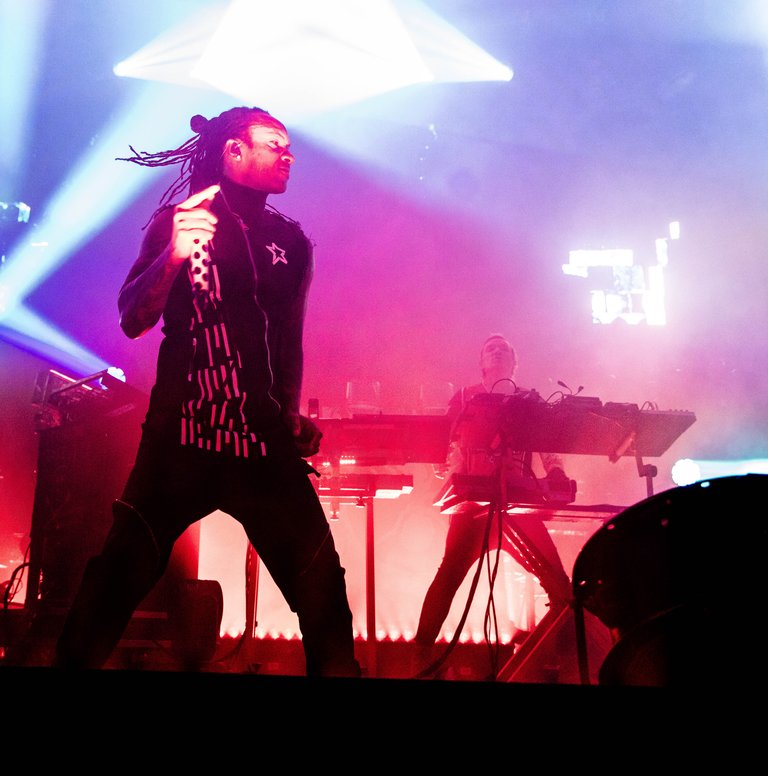 Dreadlocked singer on stage, blue and red stage lighting.