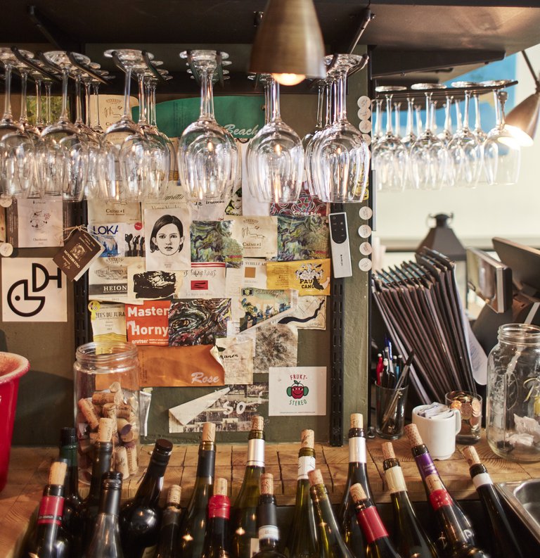 A detail showing hanging wine glasses and pictures on the walls at Tyge&Sessil, a restaurant in Stockholm.