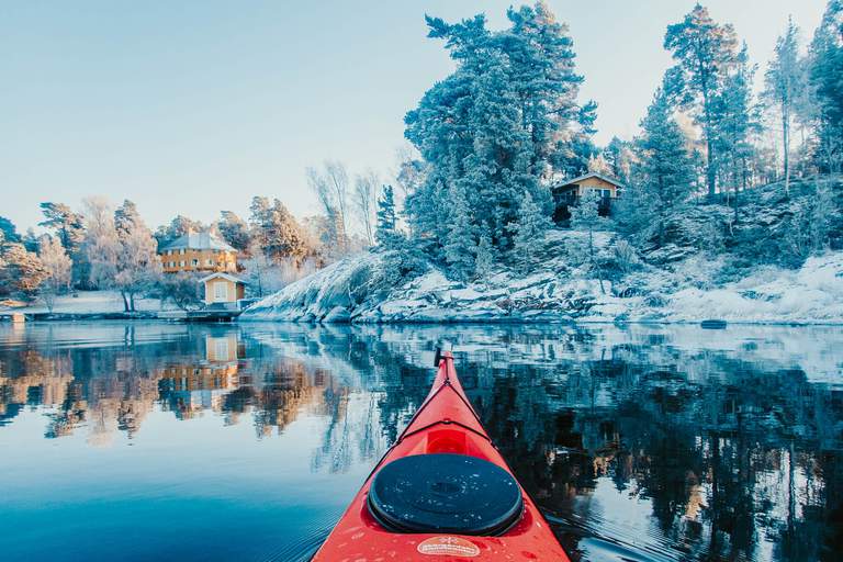 Kayak on the water at a shore covered in snow.