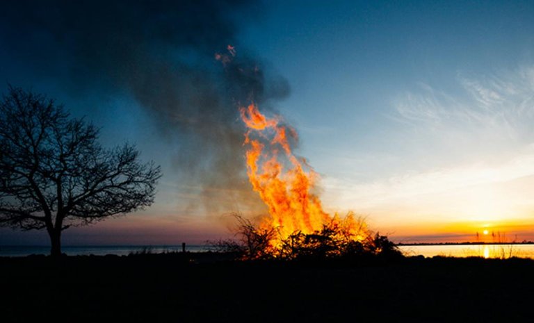 Walpurgis Night bonfire by the water. Sunset.