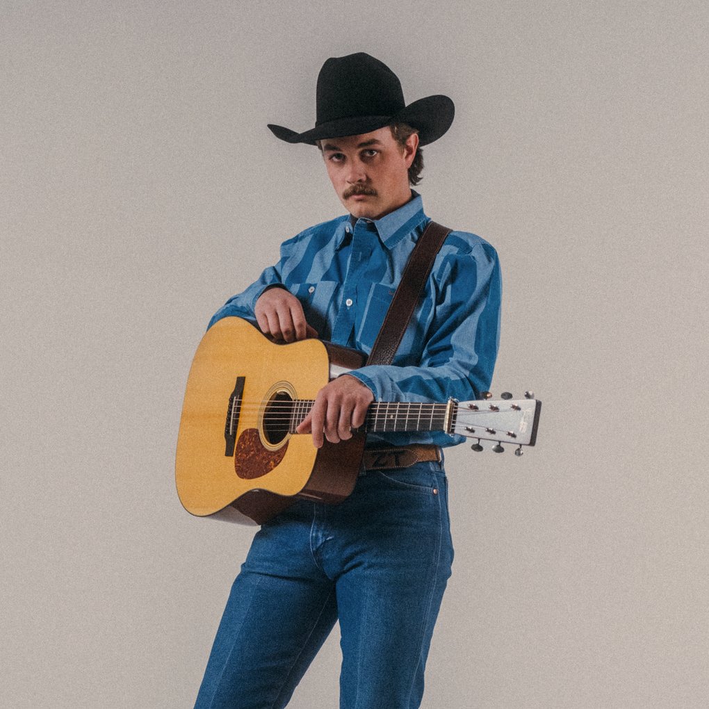 A man with a cowboy hat holding a guitar.